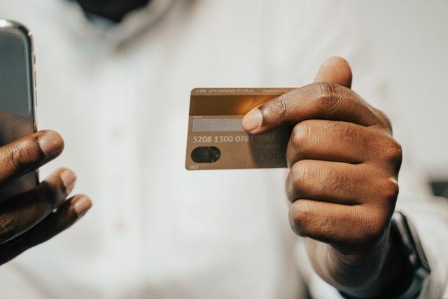 A person holding a credit card and a phone